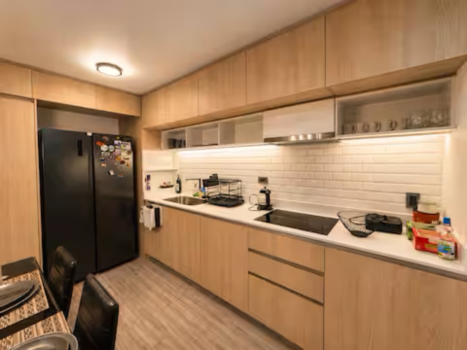 Cocina equipada con muebles de madera clara, refrigerador y encimera